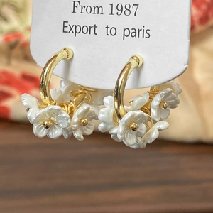 Floral hoop earrings with shell-effect white petals and gold beads on a display card