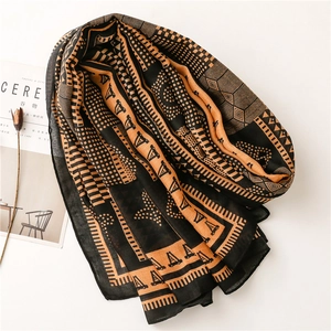 Détail d'une écharpe en lin doux avec motifs géométriques, pois et contraste orange et noir