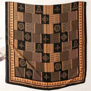 Détail de l'écharpe en coton-lin avec motifs géométriques et contraste orange et noir