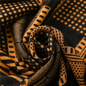 Détail de texture d'une écharpe à motifs géométriques en tissu tissé orange et noir