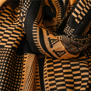 Détail de la texture d'une écharpe à motifs géométriques noir et jaune moutarde doux