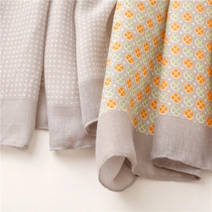 Detail of soft clover scarf fabric with geometric orange and green circle patterns