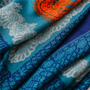 Detailed close-up of retro bohemian scarf with blue paisley and orange abstract pattern