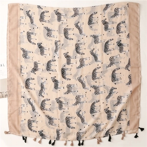 Close-up of beige zebra print scarf featuring decorative black and beige fringe tassels