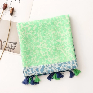 Detailed flat lay of floral paisley scarf featuring colorful tassels and light fabric