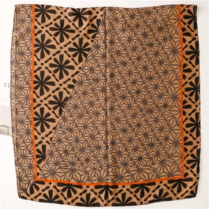 Detail view of khaki cotton-linen scarf with black floral prints and orange borders