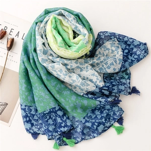 Floral paisley shawl with tassels in blue and green tones on a white minimalist background
