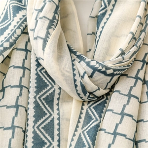 Close-up of lightweight beige shawl featuring blue geometric grid and triangle patterns