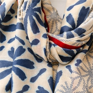 Detail view of cotton linen scarf with blue floral prints and red stitched edges