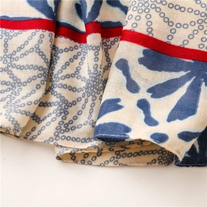 Close-up of lightweight cotton-linen scarf with blue floral prints and red striped edges