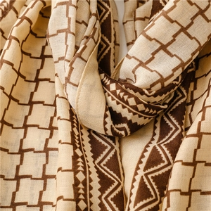 Close-up of beige and brown geometric patterns on a lightweight woven plaid scarf