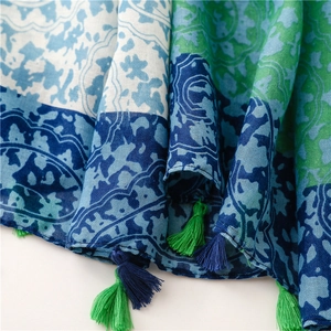Detailed close-up of blue and green floral linen scarf with handmade tassels