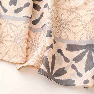 Detailed close-up of beige cotton linen scarf with grey floral and dot pattern