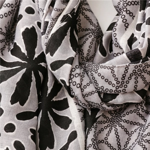 Macro detail of breathable fabric scarf featuring black floral and grid pattern texture