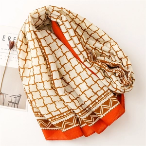 Close-up of soft plaid scarf fabric with orange edge detail and geometric patterns