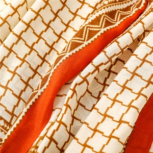 Detail of British plaid scarf with orange zigzag border and soft cotton-linen texture