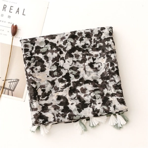 Dettaglio di sciarpa con motivo artistico a inchiostro e delicate nappe verde chiaro