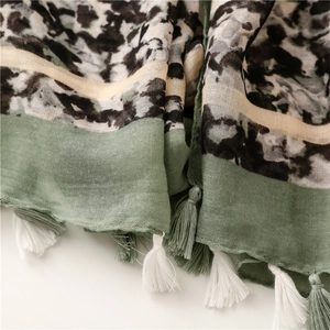 Dettaglio di sciarpa leopardata verde e beige con frange e trama del tessuto definita