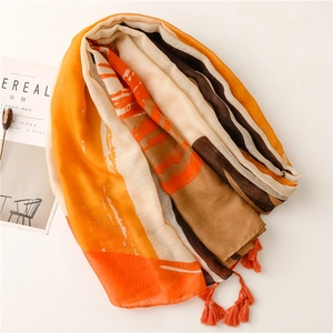 Orange sunset print scarf with gold shimmer, tassels, and abstract patterns