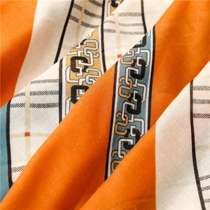 Détail d'une écharpe douce au toucher lin avec motifs chaînes orange et texture à carreaux