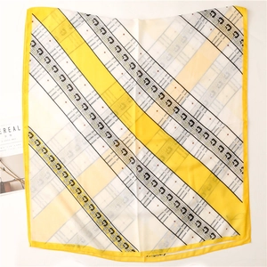 Détail d'un foulard carré à rayures jaunes et blanches avec motifs de chaînes