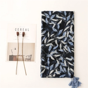 Navy blue linen scarf with leaf prints and tassels next to a Cereal magazine