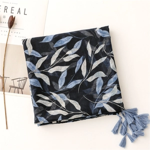 Detail of dark blue scarf with leaf pattern and tassels next to a lifestyle magazine