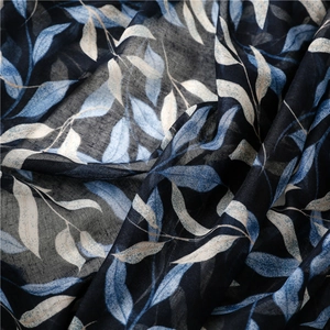 Close-up of navy blue linen-feel scarf with light blue leaf pattern and natural fabric folds