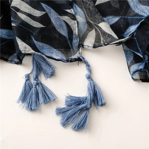 Detailed view of navy leaf print scarf with handcrafted sky blue fringe tassels