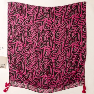 Détail de l'écharpe rose et noire avec motifs spirales abstraits et pompons décoratifs