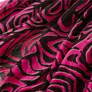 Vue macro d'un tissu léger rose rouge et noir avec motifs géométriques de vagues abstraites