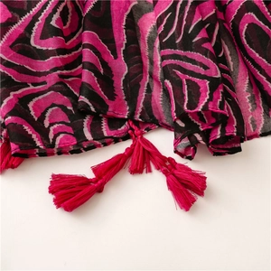 Détail d'une écharpe à motif vagues rose fuchsia avec des finitions à franges
