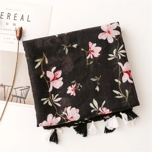 Detail of black cotton scarf featuring pink magnolia print and bicolor tassels