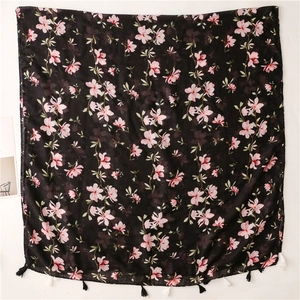 Detail of black cotton linen scarf with pink floral patterns and white handmade tassels