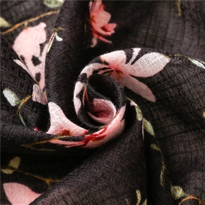 Detailed macro view of black linen floral scarf featuring pink petals and woven texture