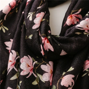 Detailed texture of black linen scarf with pink magnolia floral prints and soft folds