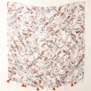 Detail view of paisley print shawl with orange and white tassel fringe and gauze texture