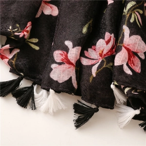 Detail of black cotton-linen scarf with floral prints and handcrafted tassels