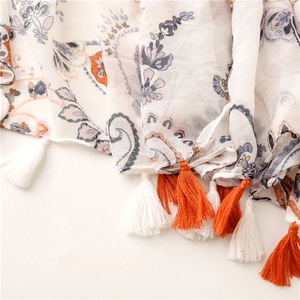 Detail of white paisley cotton scarf with orange tassels and bohemian floral patterns