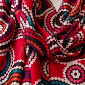 Detail of red bohemian scarf with colorful geometric circles and soft texture fabric
