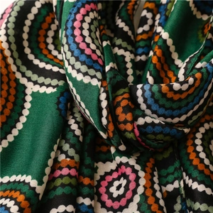 Macro shot of colorful geometric circle patterns and soft woven texture on a dark green scarf