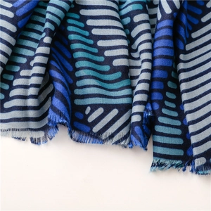 Macro detail of striped cotton-linen scarf showing soft blue fabric texture and frayed edges