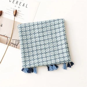 Detail of blue and white geometric snowflake pattern scarf with braided tassels