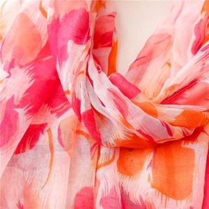 Vue détaillée d'une écharpe en mousseline rose à motifs floraux et bords cousus