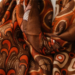 Detail of bohemian paisley scarf with warm orange and brown tones and soft cotton texture