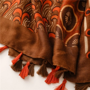 Close-up of bohemian paisley printed scarf featuring orange tassels and cotton texture