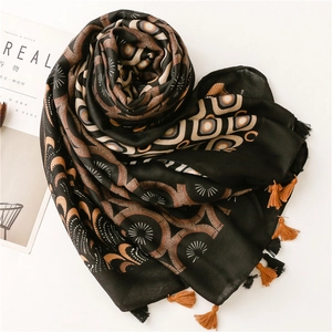 Detail of bohemian black and brown patterned scarf with handmade tassels on a white surface
