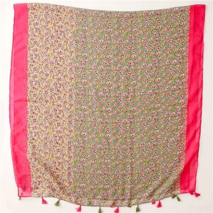 Detail of colorful floral print scarf with vibrant pink borders and soft tassel trim