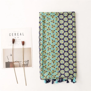 Linen feel scarf with blue geometric prints and tassels shown on a minimalist white backdrop