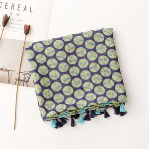 Detail of navy blue cotton scarf featuring yellow dots and decorative fringe tassels